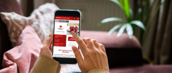 Hände halten Smartphone und Screen zeigt Roteskreuz Startseite