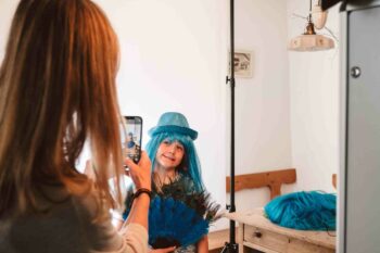 Mutter fotografiert Kind mit türkiser Perücke