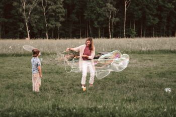 Mutter und Sohn spielen mit riesigen Seifenblasen auf der Wiese